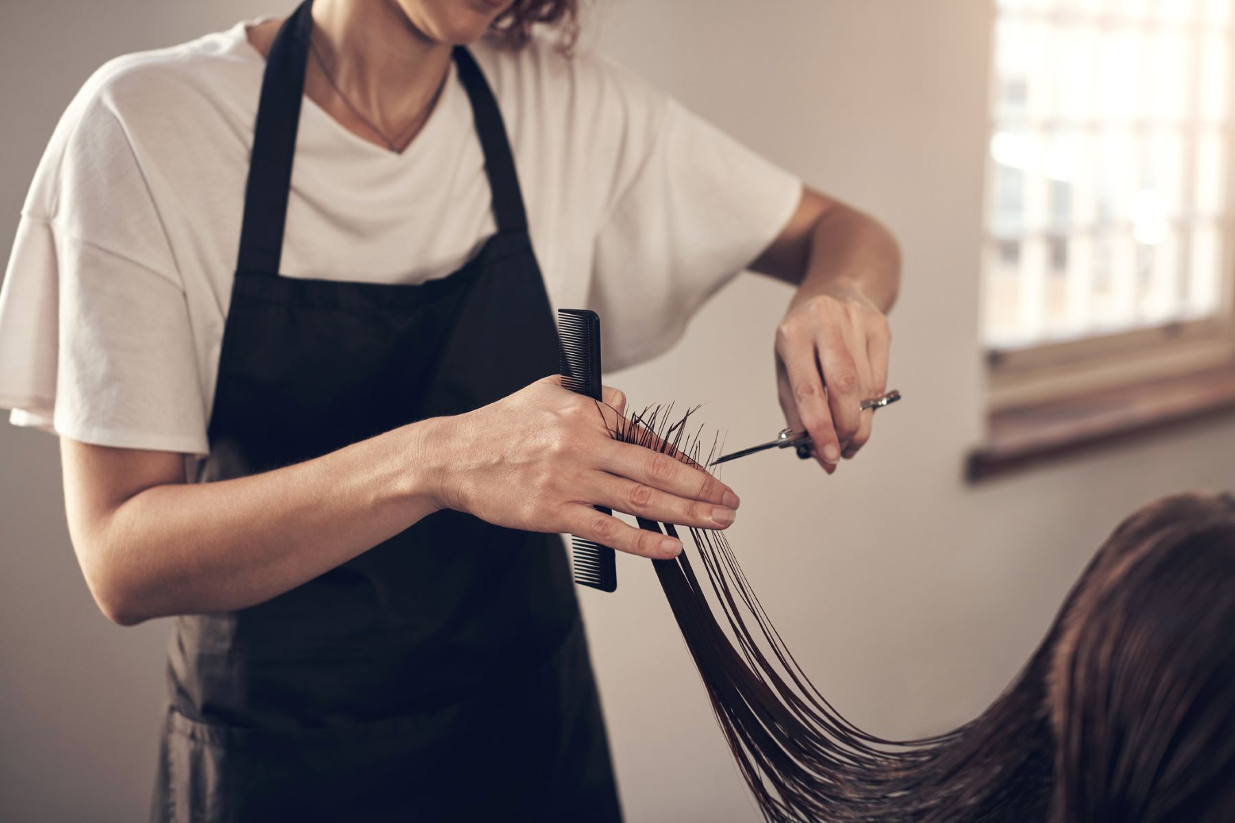hair stylist trimming client&rsquo;s ends